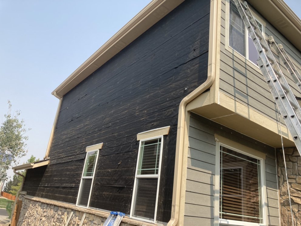 Siding prep and stain next to finished gray siding